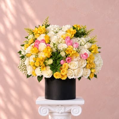 Yellow, white, and pink flowers arranged in a black vase
