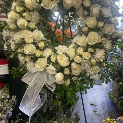 White rose and carnation wreath with a sheer ribbon bow