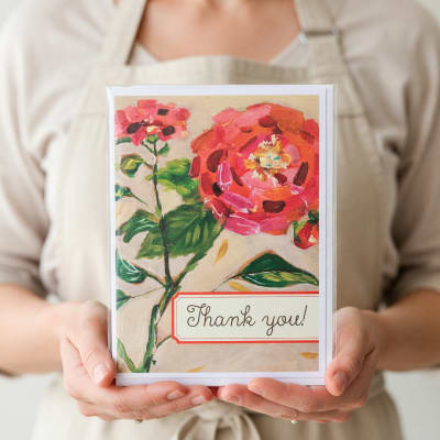 Person holding a floral thank-you card with pink flowers