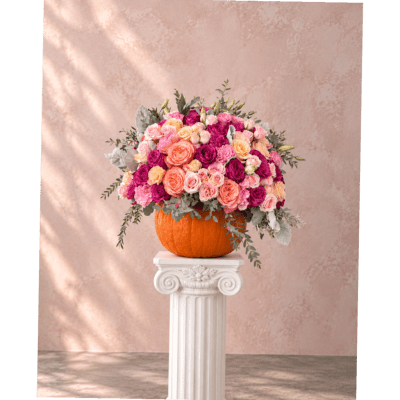 Pink and peach rose arrangement in a pumpkin vase on a pedestal