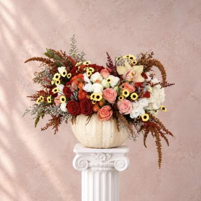 Mixed roses and small daisies arranged in a white pumpkin vase