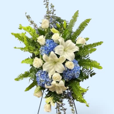 White lilies and roses with blue hydrangeas in a standing spray