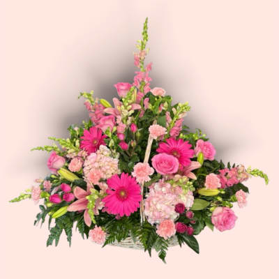 Pink mixed flower arrangement in a white basket
