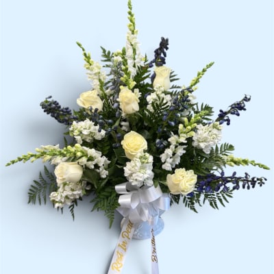 White roses and blue-white snapdragons in a vase with a ribbon