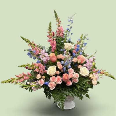 Large pastel floral arrangement in a white pedestal vase