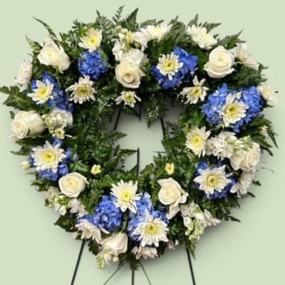 Heart-shaped floral wreath with white roses, blue hydrangeas, and white daisies