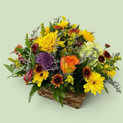Mixed flower arrangement in a wicker basket with yellow and orange blooms