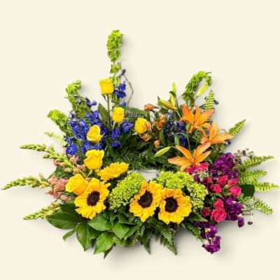 Colorful mixed flower arrangement with sunflowers, roses, lilies, and blue blooms