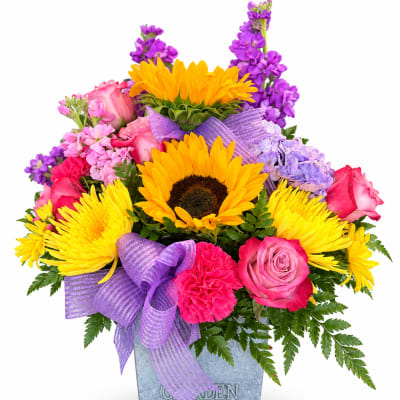 Bright mixed bouquet with sunflowers, pink roses, and purple flowers in a metal container
