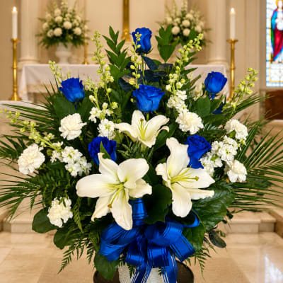 White lilies and blue roses in a vase with a blue ribbon