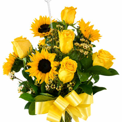 Yellow roses and sunflowers in a glass vase with a yellow ribbon