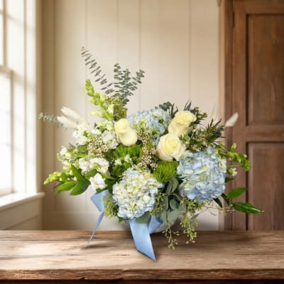 Blue and white floral arrangement in a vase with a ribbon