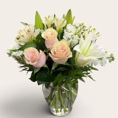 Pink roses and white lilies arranged in a clear glass vase
