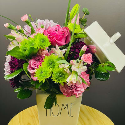 Pink and green mixed bouquet in a white container labeled HOME
