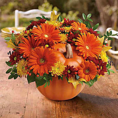 Orange and yellow flowers arranged in a pumpkin-shaped container