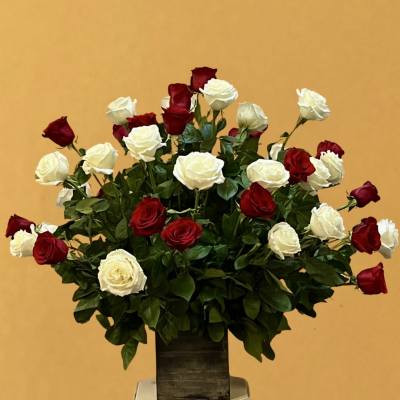 Red and white roses arranged in a tall vase on a pedestal