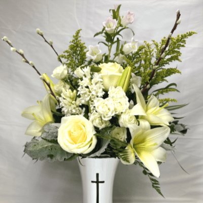 White and pale yellow lilies and roses in a white vase with a black cross motif