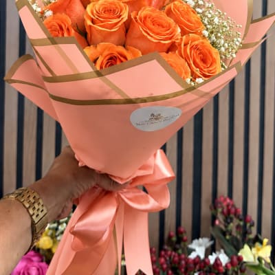 Orange roses wrapped in pink paper with a satin ribbon