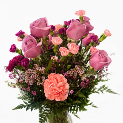 Pink roses and carnations arranged in a clear glass vase
