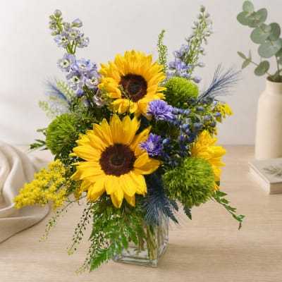 Bouquet of sunflowers and purple flowers in a clear glass vase