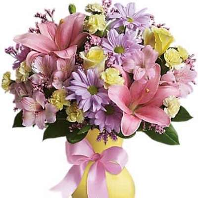 Pastel bouquet of pink lilies, yellow carnations and lavender daisies in a yellow vase with pink bow