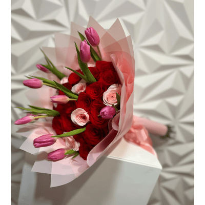 Bouquet of red roses and pink tulips wrapped in pale pink paper