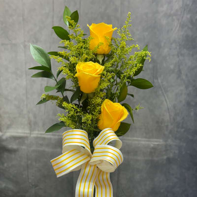 Three yellow roses with greenery and a striped ribbon bow