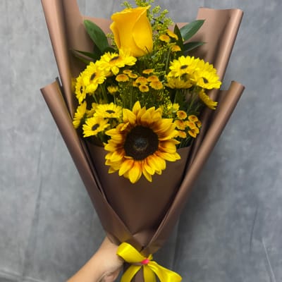 Yellow sunflower and daisy bouquet wrapped in brown paper