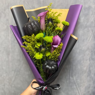 Bouquet with purple calla lilies, green mums, and black pumpkin decorations