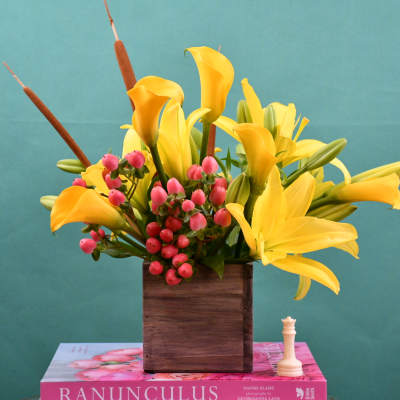 Yellow calla lilies and pink berries in a wooden box vase
