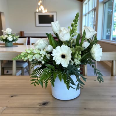 White roses and gerbera daisies arranged in a white vase