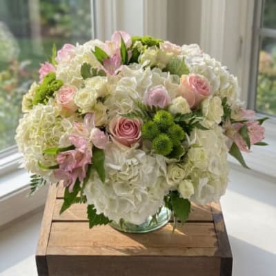 Round bouquet of white hydrangeas and pink roses in a glass vase