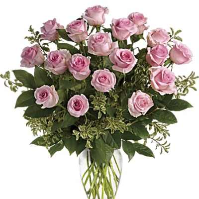 Pink roses arranged in a clear glass vase with greenery