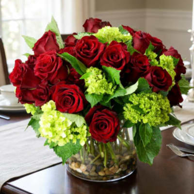 Red roses and green hydrangeas in a clear glass vase