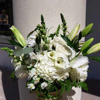 White floral arrangement with lilies, roses, and calla lilies in a striped vase