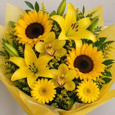 Yellow bouquet with sunflowers, lilies, and orchids wrapped in yellow paper