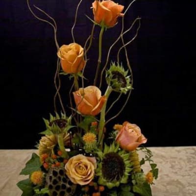 Orange roses and sunflowers in a tall floral arrangement