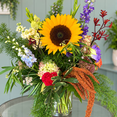 Colorful mixed bouquet with a large sunflower in a clear glass vase