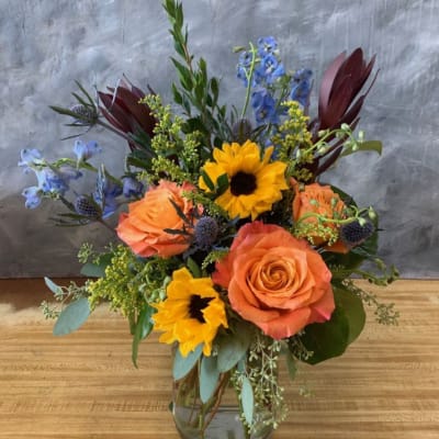 Bouquet of orange roses and yellow sunflowers in a glass vase