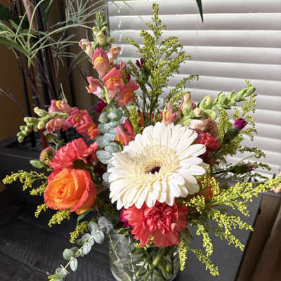 Mixed bouquet in a clear glass vase with a white gerbera and pink-orange blooms