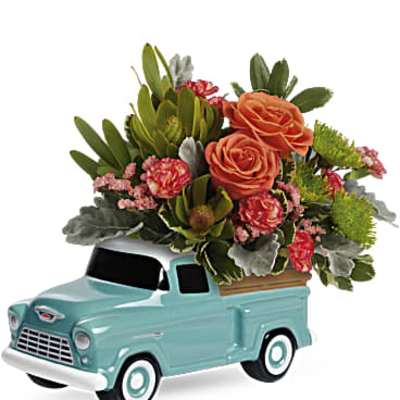 Mini turquoise pickup truck holding a mixed flower arrangement