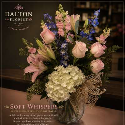 Pink roses, lilies, blue delphinium, and white hydrangea in a glass vase
