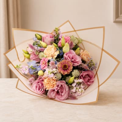 Mixed pastel bouquet wrapped in clear paper with gold trim