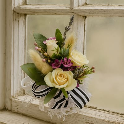 Small floral arrangement with cream roses, purple accents, and a black-and-white ribbon