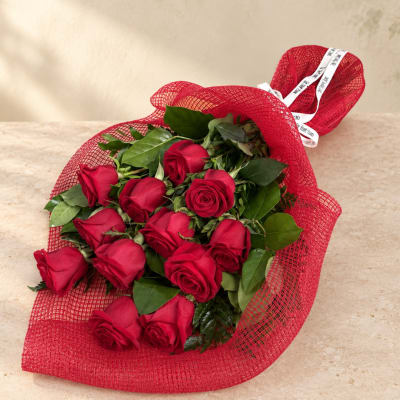 Bouquet of red roses wrapped in red mesh with a white ribbon