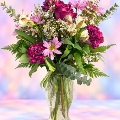 Mixed pink and white flowers arranged in a clear glass vase
