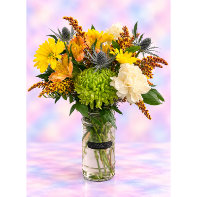 Mixed bouquet of yellow, cream, and orange flowers in a glass vase