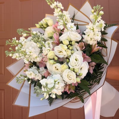 Bouquet of white and pale pink flowers wrapped in white paper