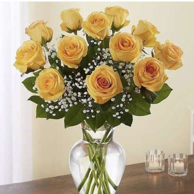 Yellow roses arranged in a clear glass vase with baby's breath