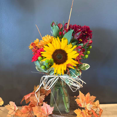 Sunflower bouquet in a glass vase with orange and burgundy flowers